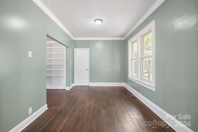 empty room featuring ornamental molding and dark wood-type flooring