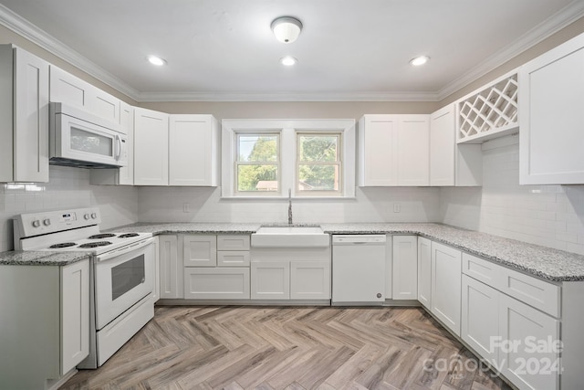 kitchen with white appliances, white cabinetry, and sink