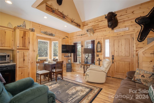 living room with wood walls, light hardwood / wood-style flooring, and vaulted ceiling