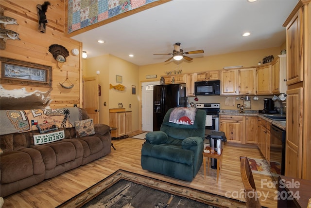 living room with wood walls, ceiling fan, sink, and light hardwood / wood-style floors