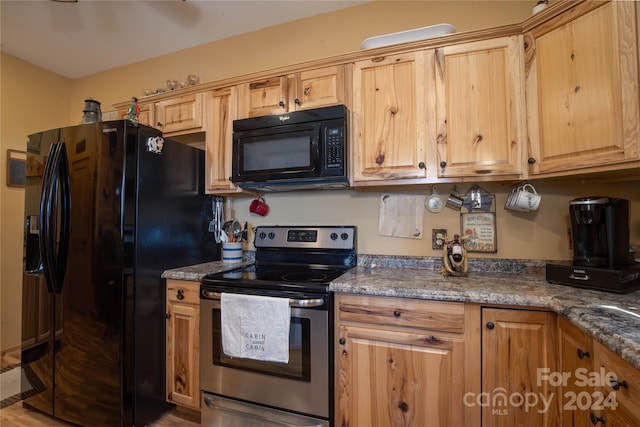 kitchen featuring light brown cabinets, black appliances, hardwood / wood-style flooring, and dark stone countertops