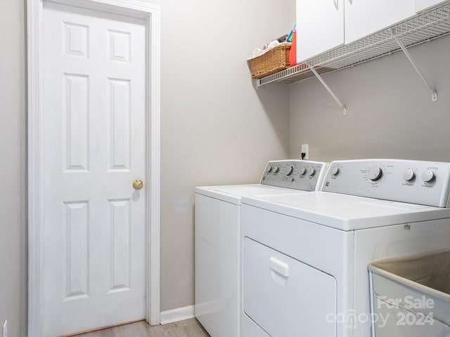 clothes washing area with light hardwood / wood-style floors, washing machine and dryer, and cabinets