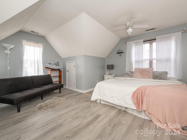 bedroom featuring ceiling fan, multiple windows, light hardwood / wood-style flooring, and vaulted ceiling