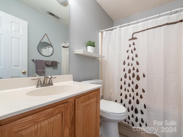 bathroom featuring wood-type flooring, a shower with curtain, vanity, a textured ceiling, and toilet