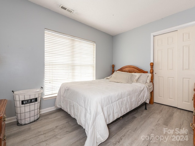 bedroom featuring hardwood / wood-style floors, multiple windows, and a closet