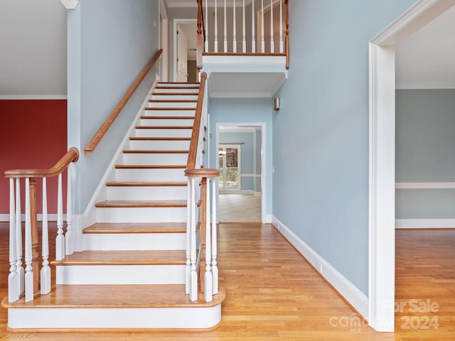 stairs featuring wood-type flooring and crown molding