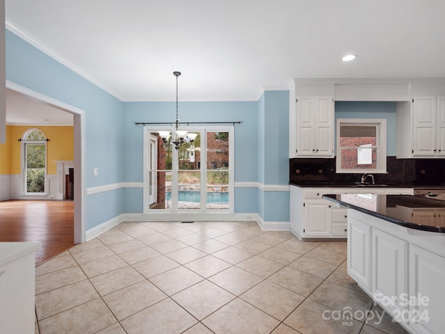 kitchen featuring tasteful backsplash, light tile patterned floors, decorative light fixtures, a notable chandelier, and white cabinetry