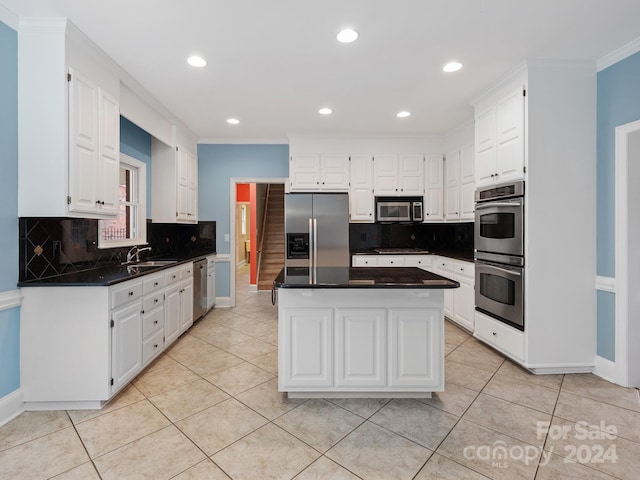 kitchen featuring white cabinets, stainless steel appliances, crown molding, and sink