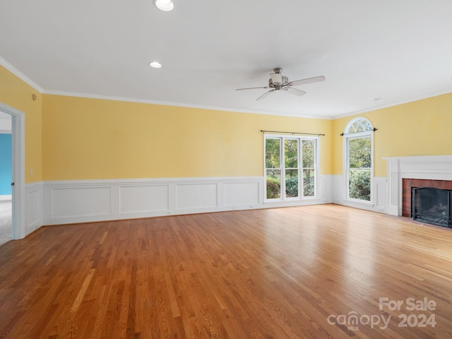 unfurnished living room with crown molding, hardwood / wood-style floors, ceiling fan, and a brick fireplace