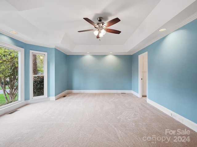 carpeted empty room featuring ceiling fan, crown molding, and a tray ceiling