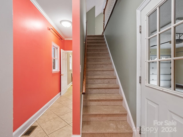 stairs featuring tile patterned floors and crown molding