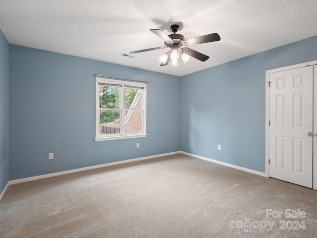 empty room with carpet, ceiling fan, and a textured ceiling