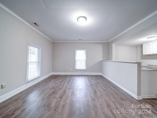 empty room featuring crown molding, plenty of natural light, and light wood-type flooring