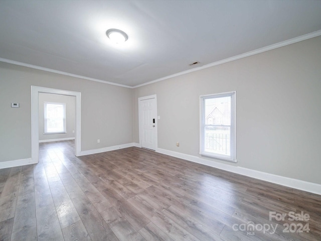 spare room with light wood-type flooring and ornamental molding