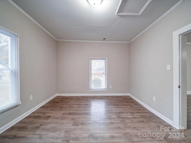 empty room featuring a healthy amount of sunlight, crown molding, and light hardwood / wood-style flooring