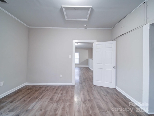 empty room with crown molding and light hardwood / wood-style flooring