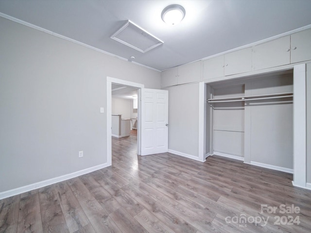 unfurnished bedroom with a closet, light hardwood / wood-style floors, and ornamental molding