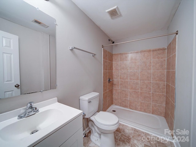 bathroom featuring toilet, vanity, and tiled shower