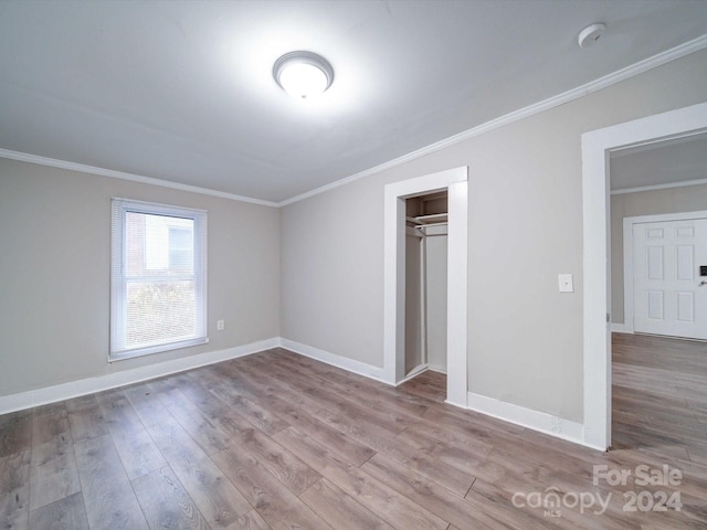 unfurnished bedroom with light wood-type flooring, a closet, and crown molding