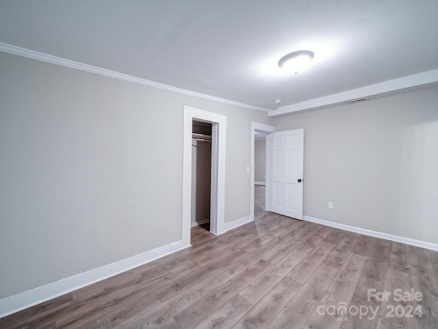 unfurnished bedroom featuring crown molding, a closet, and light hardwood / wood-style floors