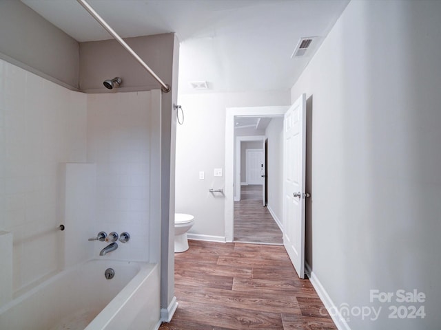 bathroom with toilet, tiled shower / bath, and hardwood / wood-style flooring