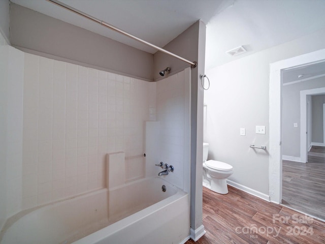 bathroom featuring hardwood / wood-style floors, tiled shower / bath combo, and toilet