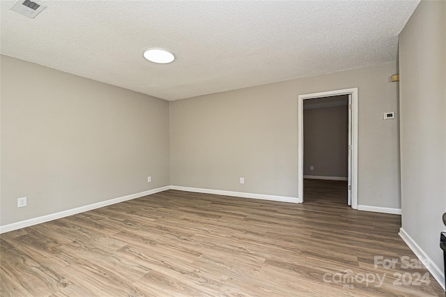 empty room with a textured ceiling and hardwood / wood-style flooring