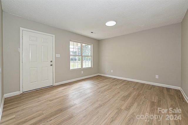 unfurnished room featuring light hardwood / wood-style floors and a textured ceiling