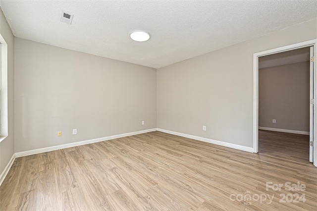 spare room featuring a textured ceiling and light wood-type flooring