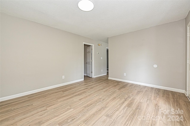 unfurnished room featuring a textured ceiling and light wood-type flooring