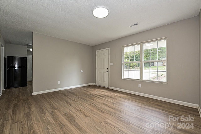 empty room featuring dark hardwood / wood-style flooring and a textured ceiling