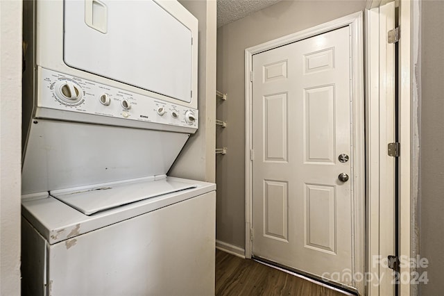 clothes washing area featuring dark wood-type flooring, a textured ceiling, and stacked washer and dryer