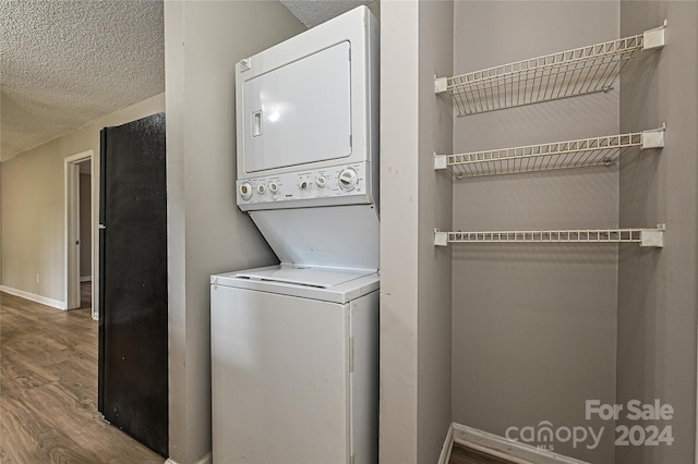 laundry area featuring stacked washer / dryer, a textured ceiling, and hardwood / wood-style flooring