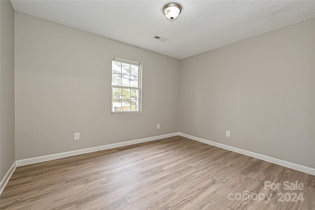 unfurnished room featuring a textured ceiling and light hardwood / wood-style floors