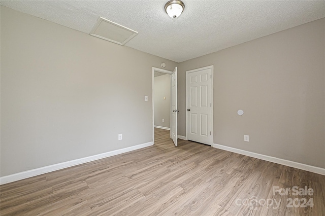 spare room with light wood-type flooring and a textured ceiling