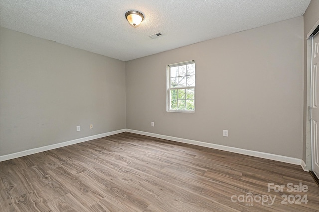 empty room with hardwood / wood-style floors and a textured ceiling