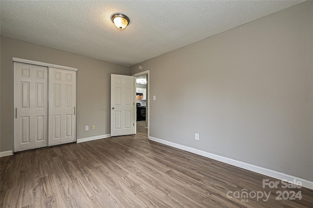 unfurnished bedroom with a closet, a textured ceiling, and hardwood / wood-style flooring