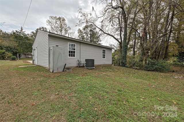 back of house featuring central AC unit and a yard