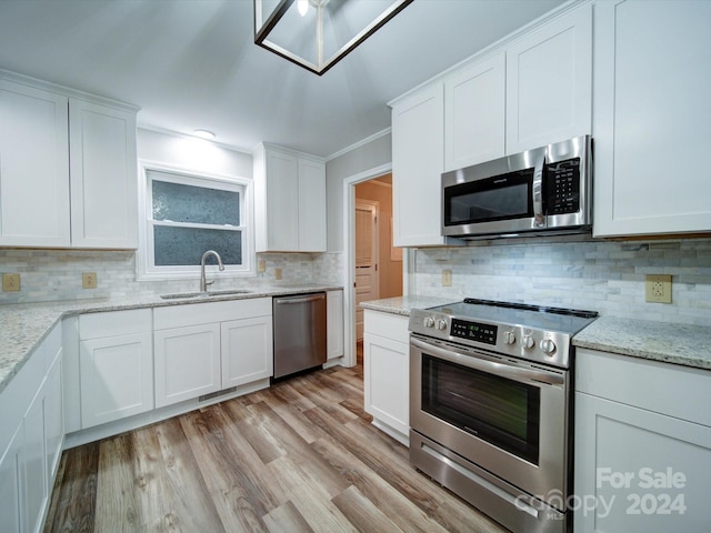 kitchen featuring stainless steel appliances, sink, light hardwood / wood-style flooring, white cabinets, and decorative backsplash