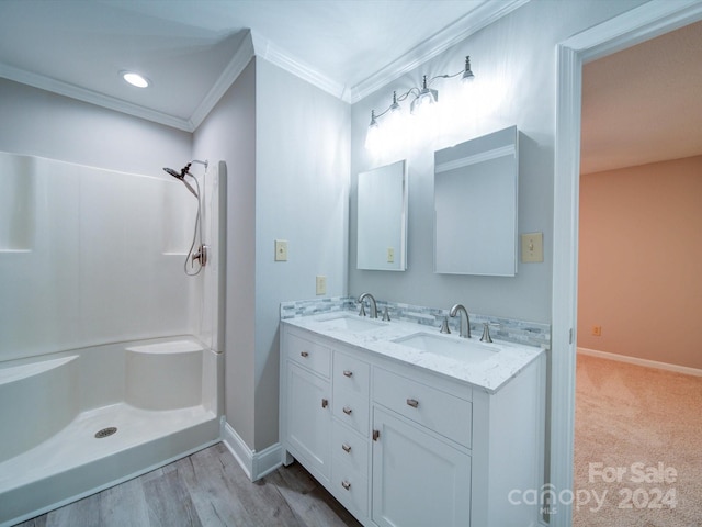 bathroom with vanity, hardwood / wood-style flooring, crown molding, and a shower