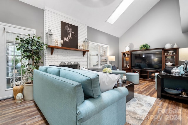 living room featuring hardwood / wood-style floors, high vaulted ceiling, a fireplace, and a skylight