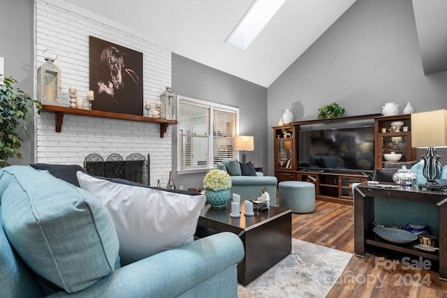 living room featuring a brick fireplace, wood-type flooring, high vaulted ceiling, and a skylight