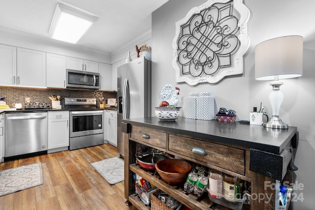 kitchen with white cabinets, light wood-type flooring, appliances with stainless steel finishes, and crown molding