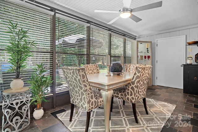 dining area featuring wooden walls and ceiling fan