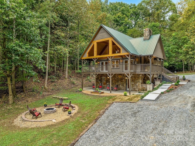 exterior space featuring an outdoor fire pit, stone siding, stairway, a chimney, and a patio area