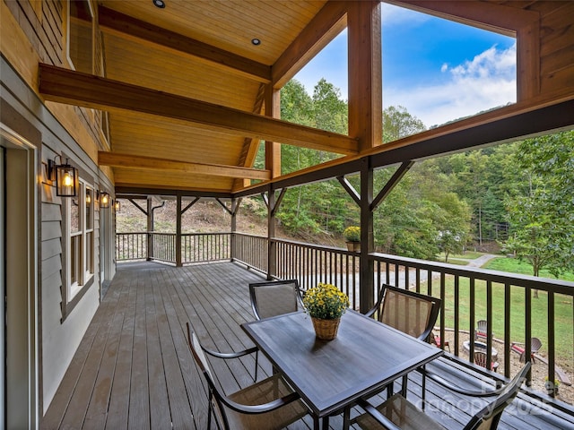 wooden terrace with outdoor dining area and a lawn