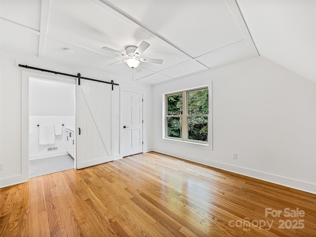 unfurnished bedroom with a barn door, visible vents, baseboards, ensuite bath, and light wood-type flooring