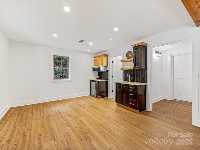 kitchen featuring visible vents, light wood-style floors, light countertops, open shelves, and stainless steel microwave