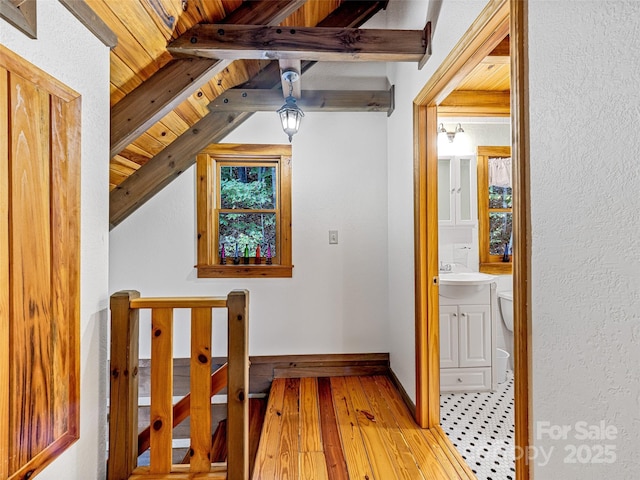 bonus room featuring vaulted ceiling with beams, light wood-style floors, a sink, wooden ceiling, and baseboards