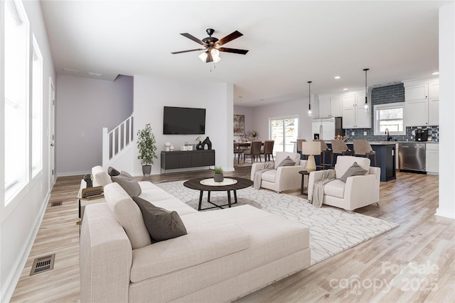 living room featuring sink, light hardwood / wood-style floors, and ceiling fan